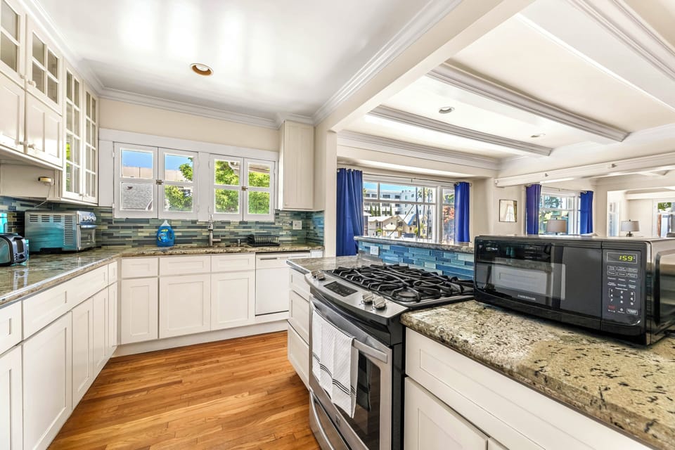 Bright kitchen with gas range, granite, and open bar to living space.