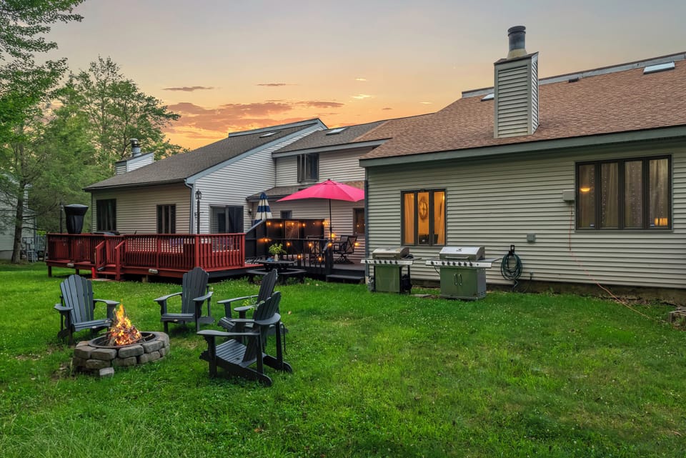 Spacious, lush backyard with a firepit, two grills, and plenty of outdoor seating for relaxing or dining al fresco.