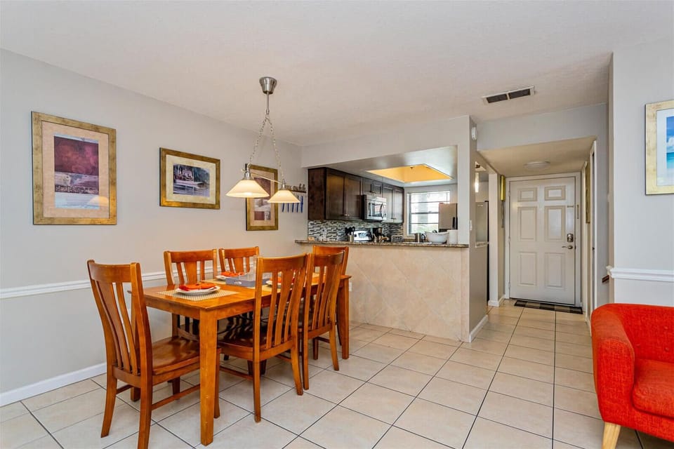 Dining area with wooden table and chairs adjacent to a kitchen with granite countertops and modern appliances.