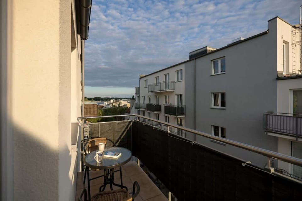 A balcony view overlooking neighboring residential buildings under a partly cloudy sky.