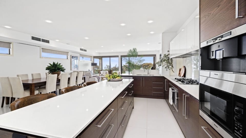 The fully equipped kitchen features a Miele oven and built-in coffee machine, gas cooktop, Nespresso pod machine, and a butler’s pantry. The large island bench with seating makes it easy to prep, serve, and socialise.