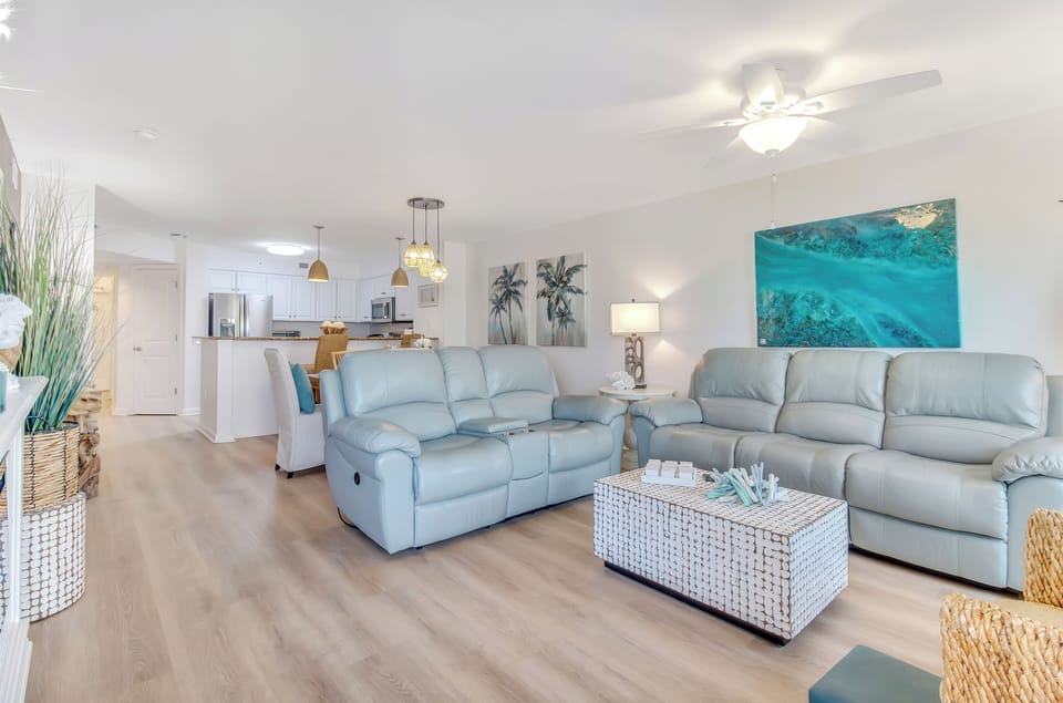Sink into plush leather seating in your bright, open living space where coastal artwork and modern comfort create your perfect retreat.