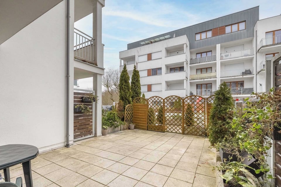 A spacious outdoor terrace with a mix of greenery and modern fencing, providing a private space to relax. Perfect for enjoying coffee or meals in the fresh air.