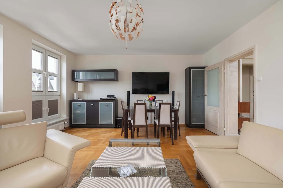 A well-lit living and dining area featuring a comfortable sofa, TV setup, and a dining table for gatherings. Modern design elements enhance the aesthetic appeal.