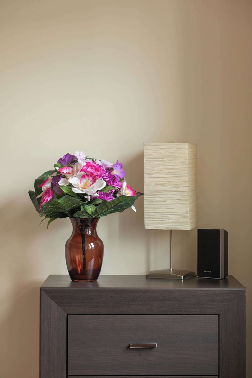 A close-up of a bedside table with a vase of fresh flowers, adding a touch of elegance. The soft lighting creates a cozy and intimate atmosphere.