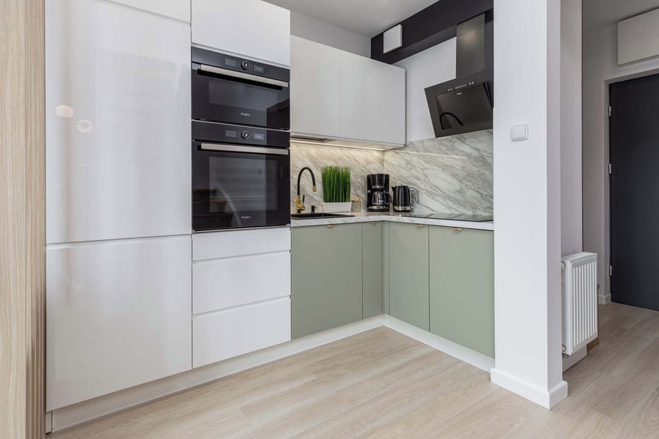 Functional kitchen with white cabinets, black worktop and modern appliances.