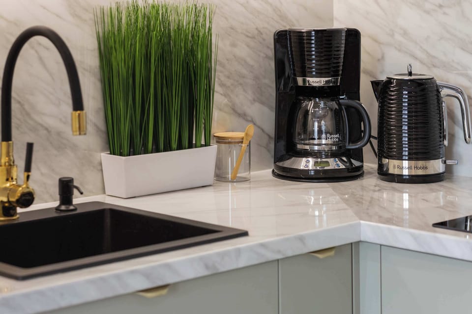 Close-up of light marble worktop with overflow coffee machine and electric kettle.