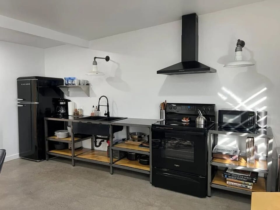 Living area open to kitchen — leather sofa, dining table, and full-size black range