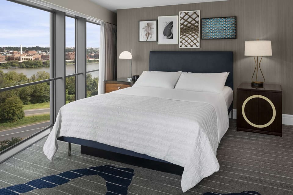 Corner king room with river views and soft gray and navy decor