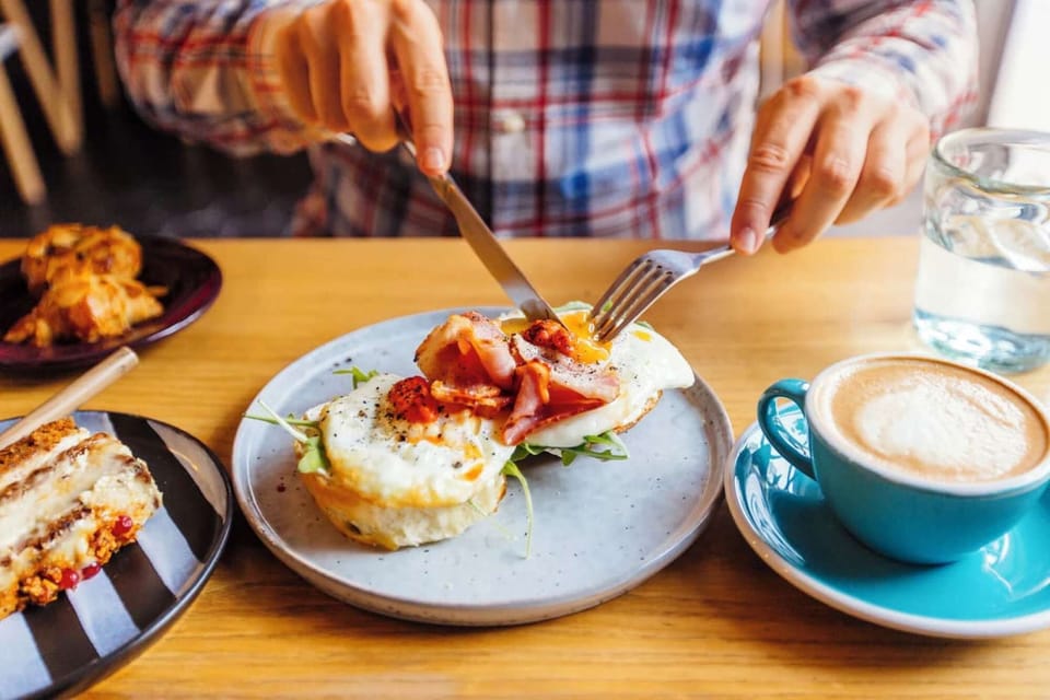 Breakfast plate with eggs, ham, coffee, and pastries on table