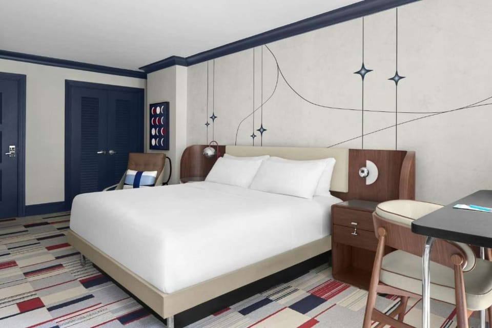 CLASSIC KING ROOM: Wide view of plush king bed, patterned accent wall, nightstands &amp; work station