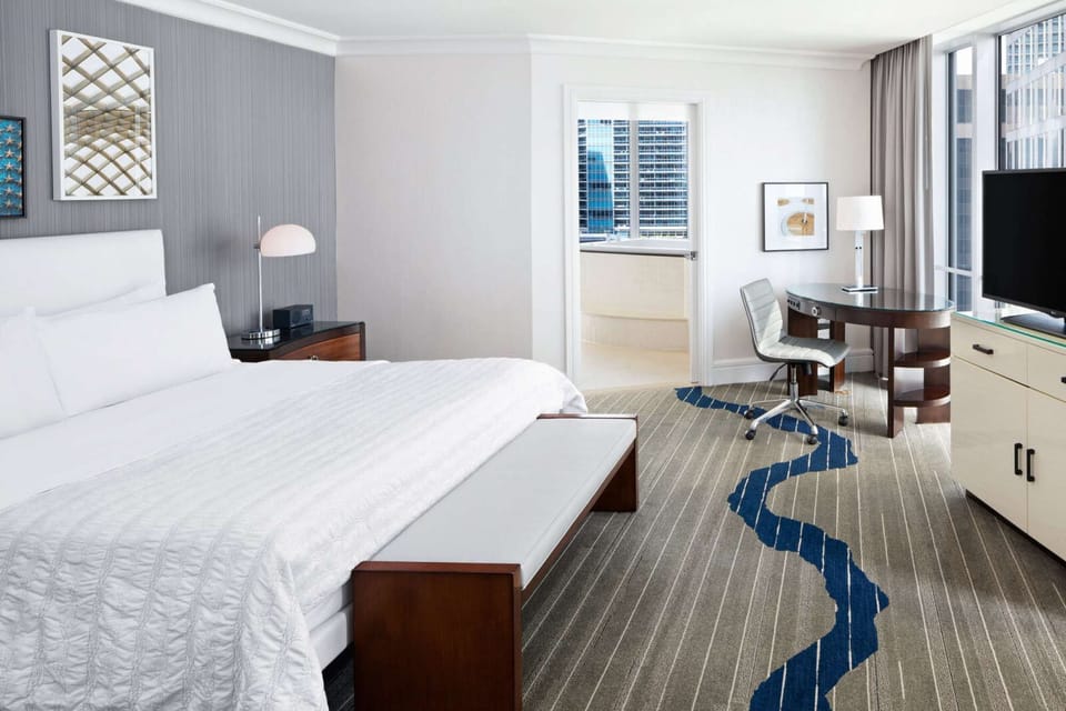 Spacious suite with king bed, desk, TV, and soaking tub view