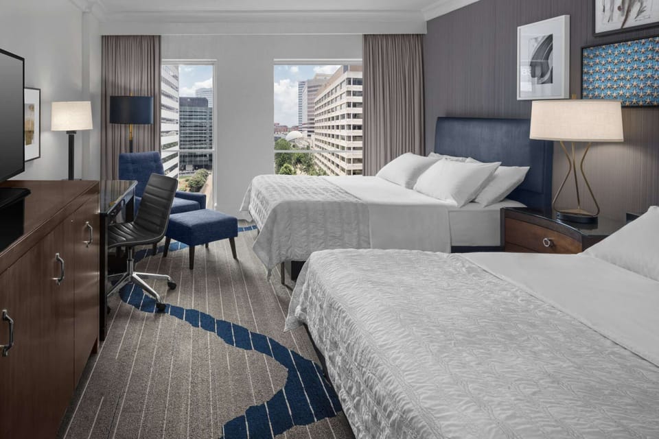 Room with two queen beds, city views, and a sleek work desk