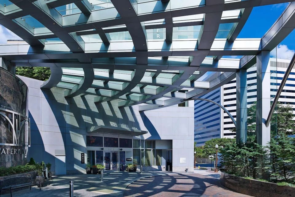 Entrance with curved glass canopy and city reflections all around