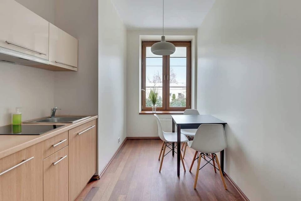 A small kitchenette with wooden cabinets, a dining table, and bright natural light.