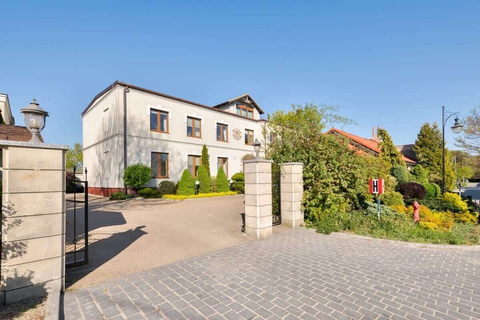 A grand building surrounded by greenery and cobblestone paths.