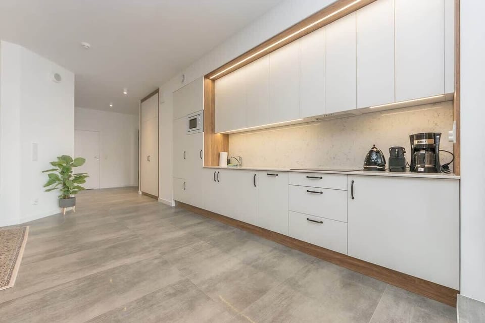 A fully equipped kitchen that blends functionality with modern aesthetics. Bright cabinets with built-in LED lighting and a marble countertop add a touch of elegance.