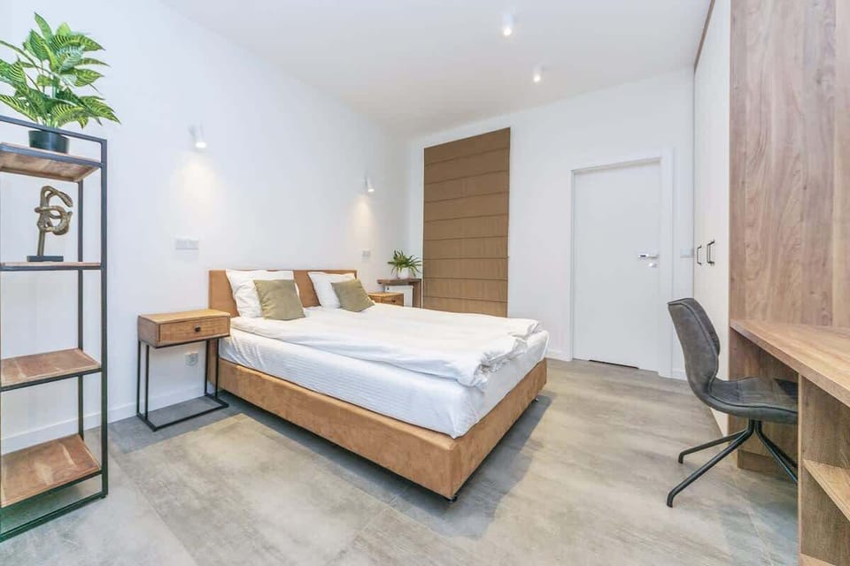 Soft, neutral wall colors and natural accents, such as potted plants and minimalist decor, create a calming atmosphere. Stylish bedside lamps on either side of the bed provide warm lighting, ideal for evening reading. 