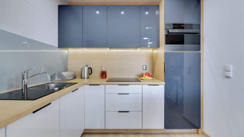 A modern kitchen with sleek white cabinets, wooden countertops, and built-in appliances. Minimalist and functional, it seamlessly integrates with the rest of the space.