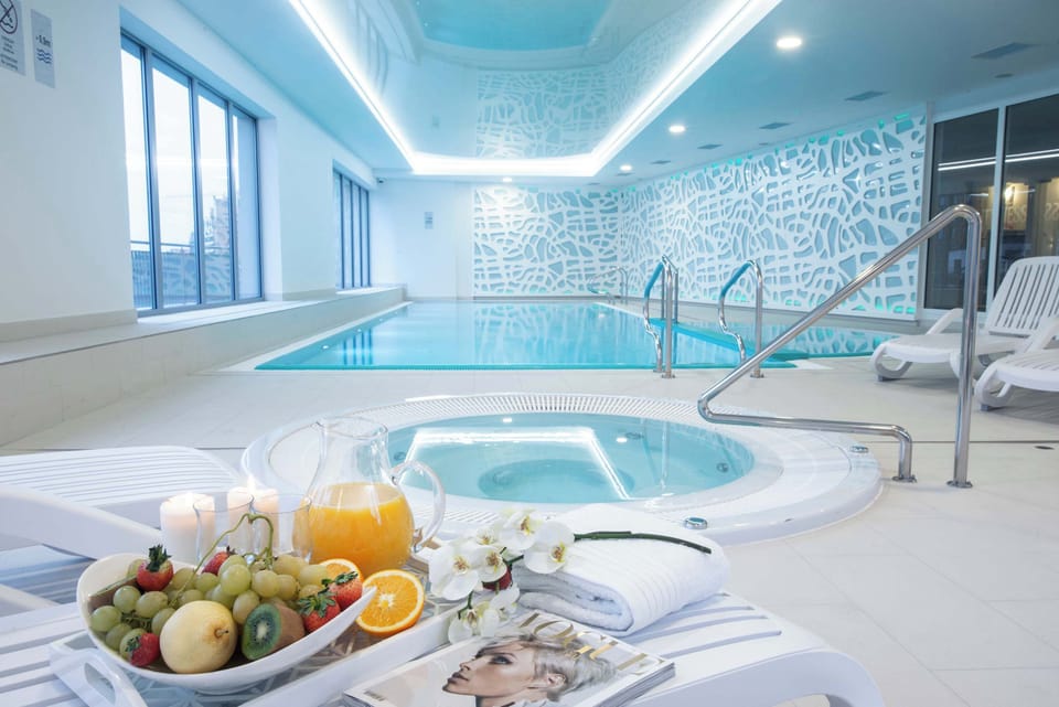 A spa-like facility with a jacuzzi, pool, and seating area, surrounded by elegant lighting and clean, modern design.