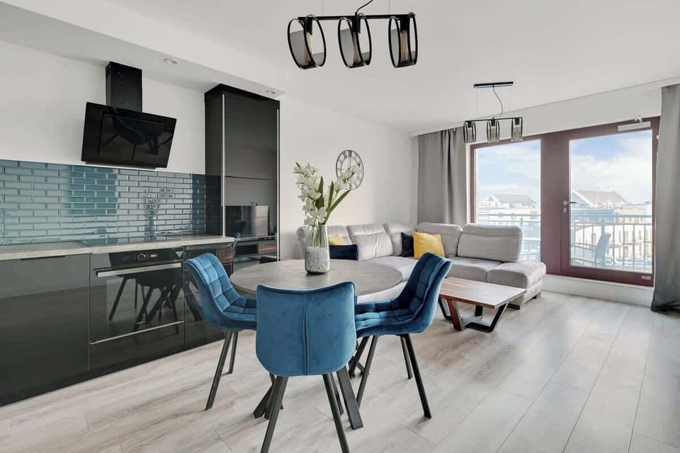 Sleek black and teal kitchen accents with plush blue velvet chairs, creating a chic and inviting atmosphere.
