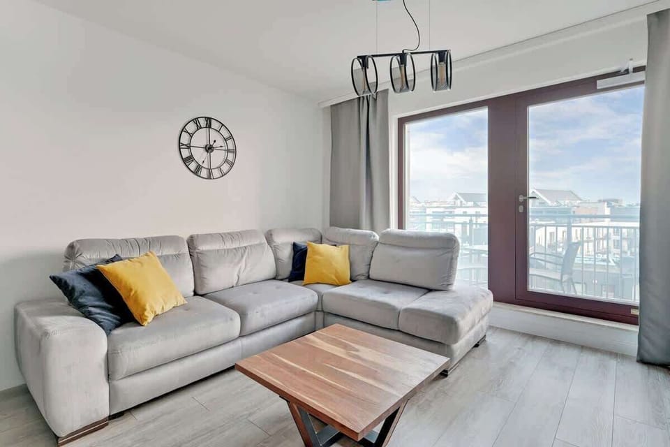 Light gray sectional sofa complemented by vibrant mustard and navy cushions, creating a sophisticated yet inviting atmosphere, with natural light flooding in through expansive windows.