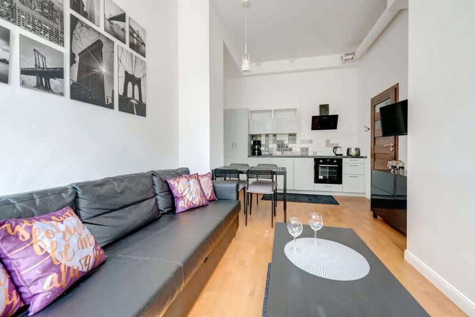 The spacious living room combines light walls with expressive, dark furniture, and decorations such as stylish graphics and colorful accents create a modern but cozy interior.