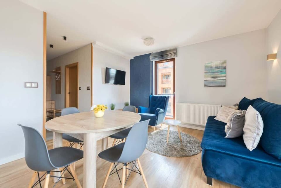 Bright, contemporary, and inviting, featuring striking blue accents, natural wood elements, and a cozy, open-plan design, perfect for relaxation and socializing.