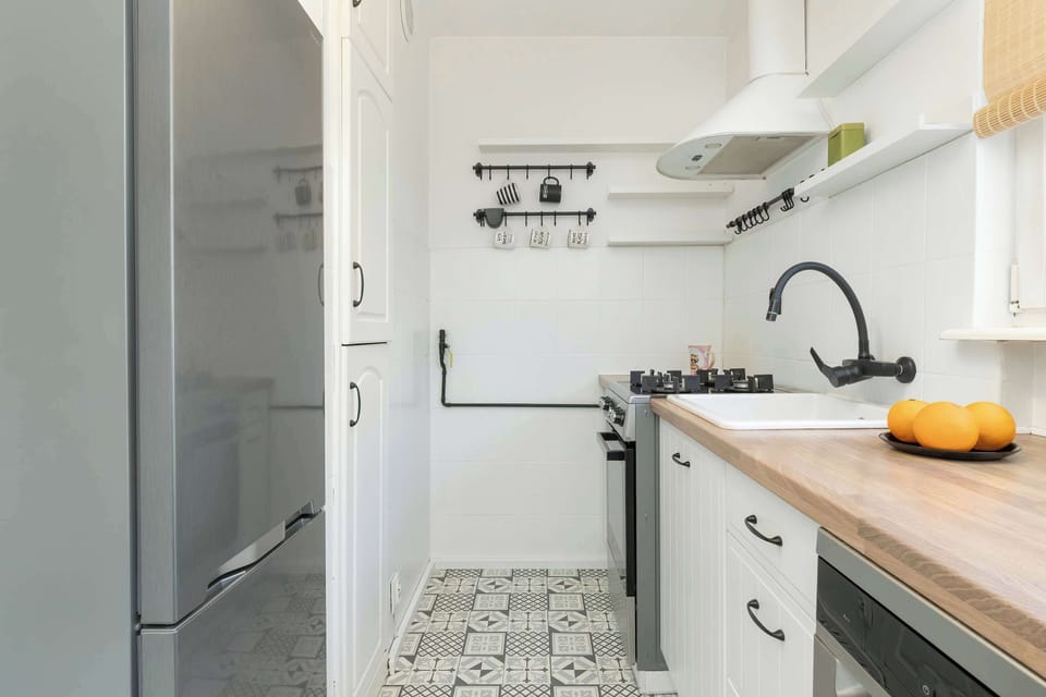 A white kitchen with a wooden countertop and modern fixtures.
