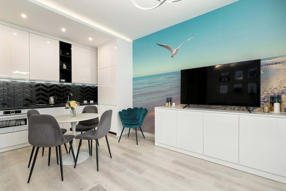 Living room with seaside elements is equipped with TV, combined with kitchenette and dining area.