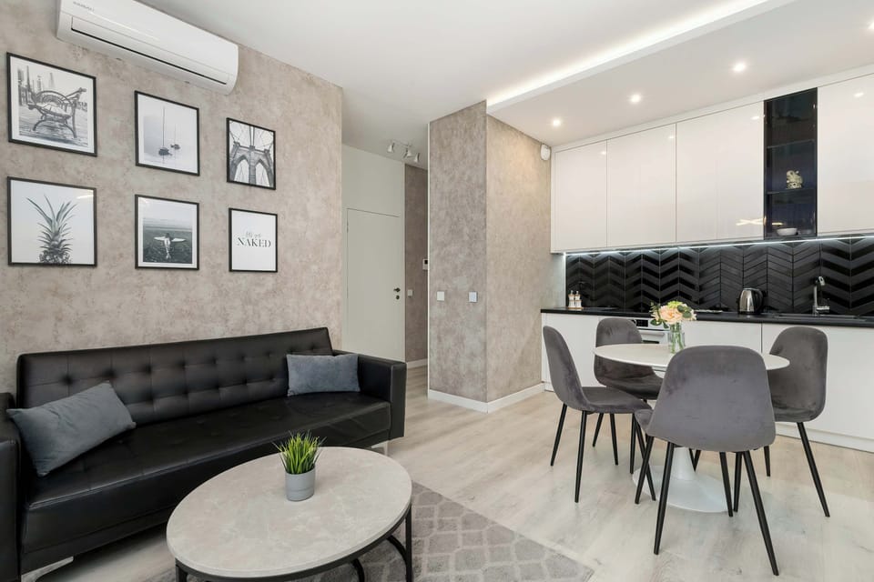Comfortable and chic living room with a sofa, coffee table, TV and kitchenette with dining area.