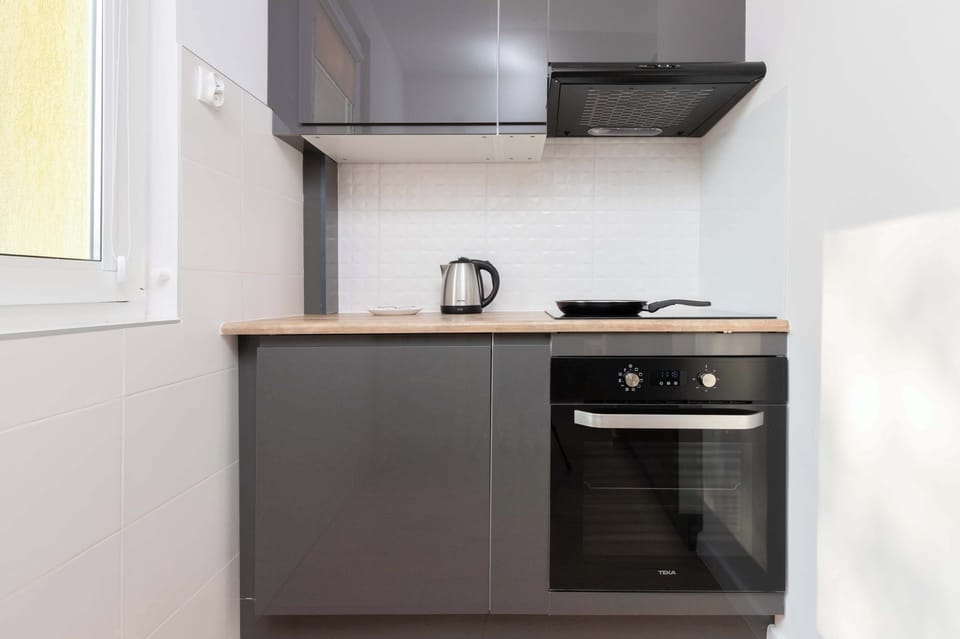 A stylish and functional kitchen area with white countertops, induction hob, and oven. The room is well-lit and perfect for preparing meals.