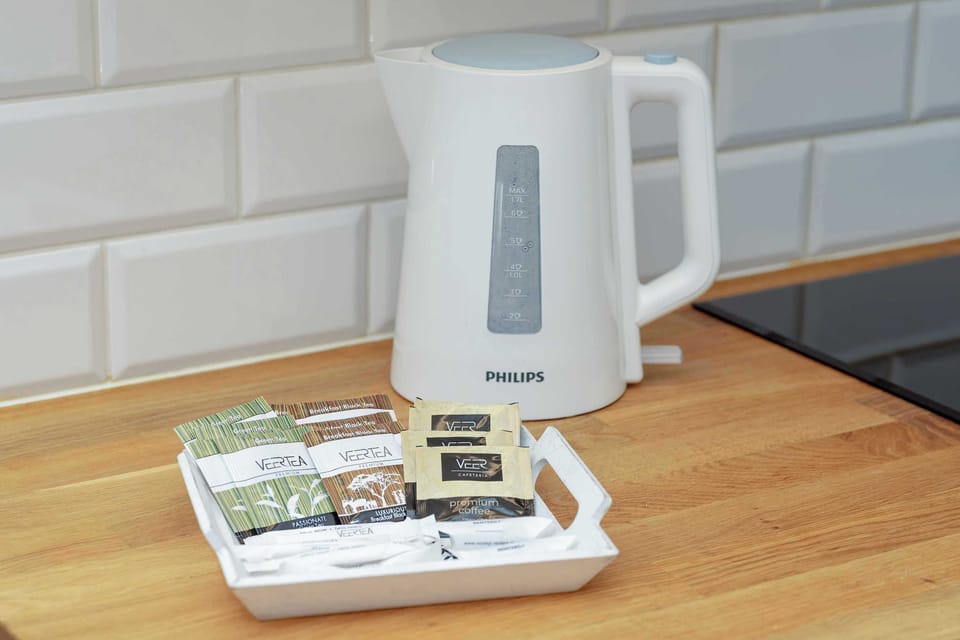 A countertop scene with a kettle, tray of tea and coffee supplies, creating a welcoming touch.