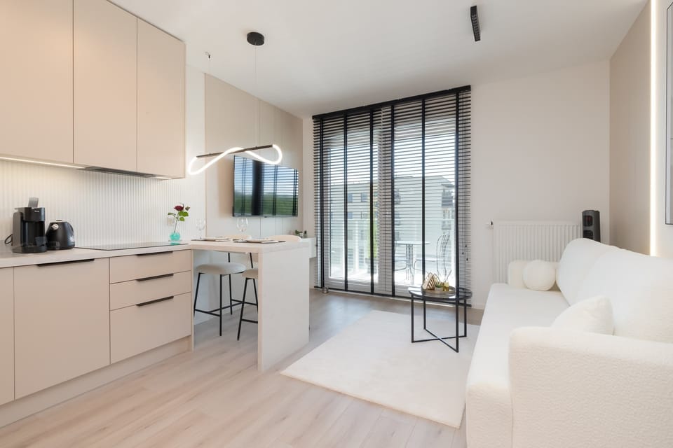 The kitchenette with light-colored cabinets and built-in appliances like dishwasher, impresses with its modern design and practical layout.