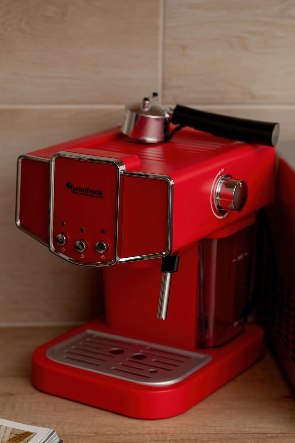 The red coffee machine, standing on a countertop with bright tiles, adds a striking colour accent to the interior.