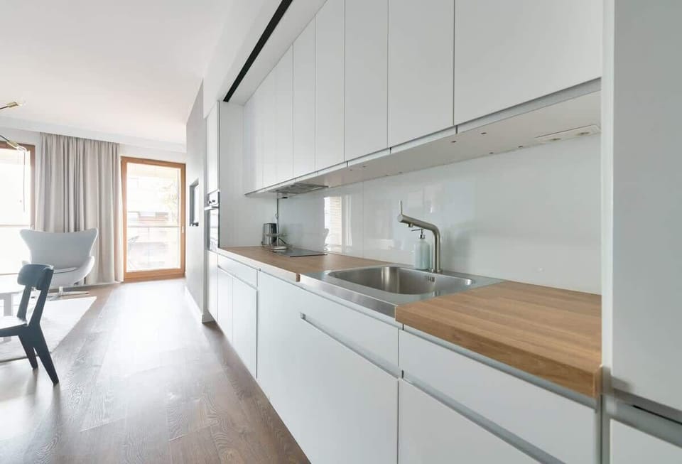 A sleek, open-concept kitchen with white cabinetry and wooden countertops. Fully equipped for any culinary needs, the kitchen is perfect for preparing meals in style.