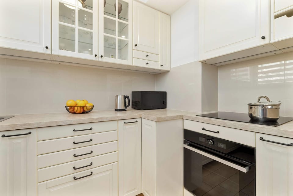 A similar view of the kitchen from a slightly different angle, highlighting the stove, kettle, and fresh fruit on the counter.

