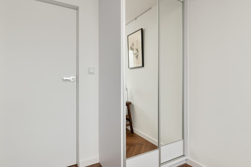 Bedroom with built-in mirrored wardrobe and minimalistic look.