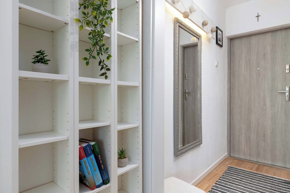 A full view of the entryway with a large mirror, coat hooks, and open shelving, emphasizing functionality and style.