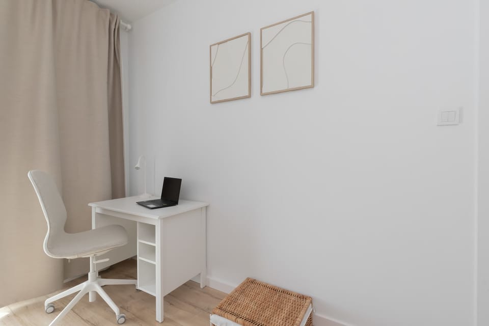 A minimalistic corner with a desk and chair next to a window.