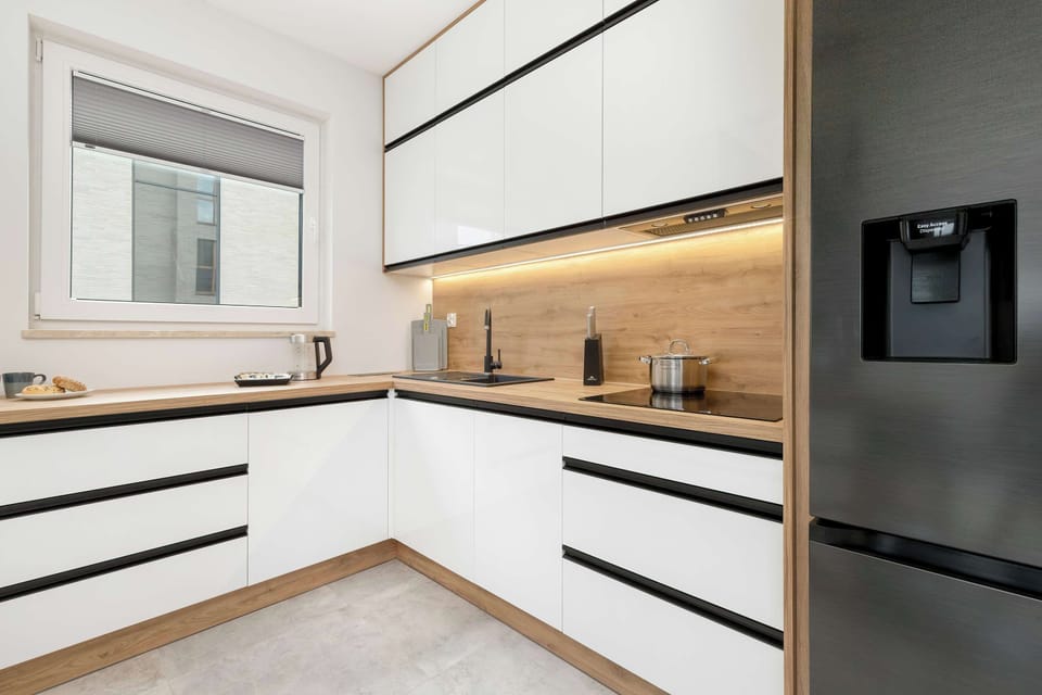 A close-up of the kitchen’s stylish black and white design. The wooden countertop and backsplash add warmth to the modern aesthetic.