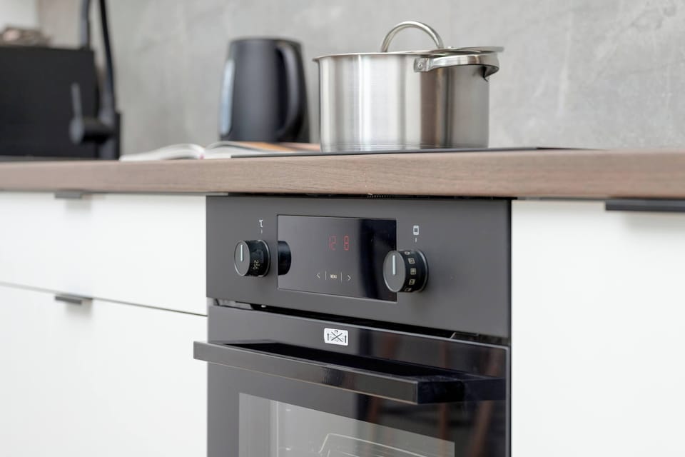 Fully equipped kitchenette with induction cooktop, oven, electric kettle, coffee maker.