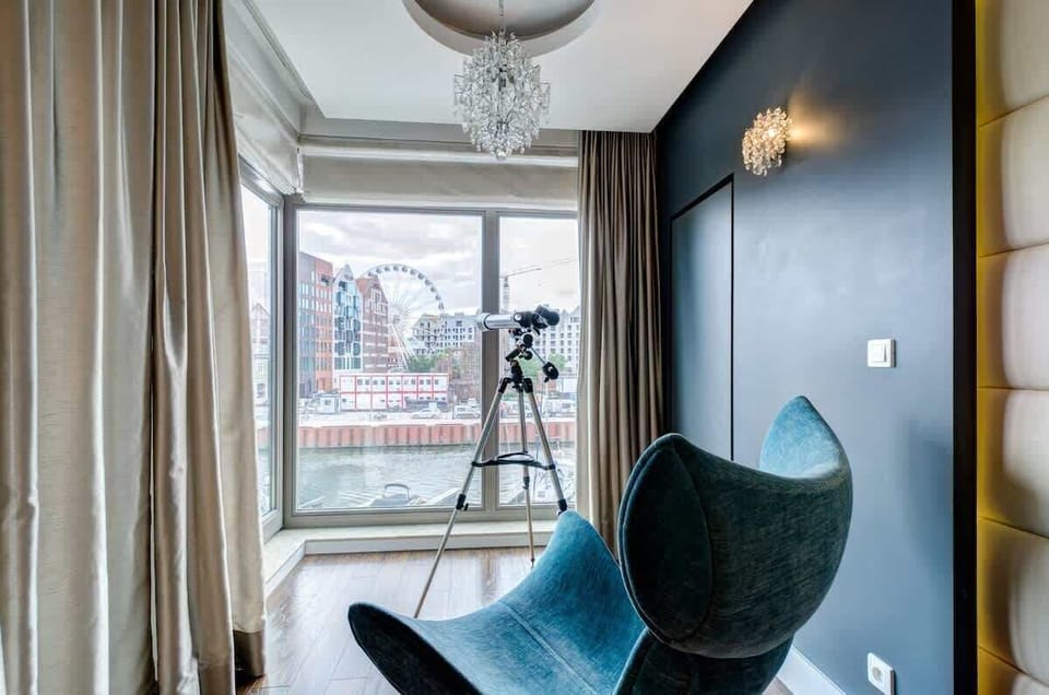 Stylish reading nook with a turquoise accent chair and city views.