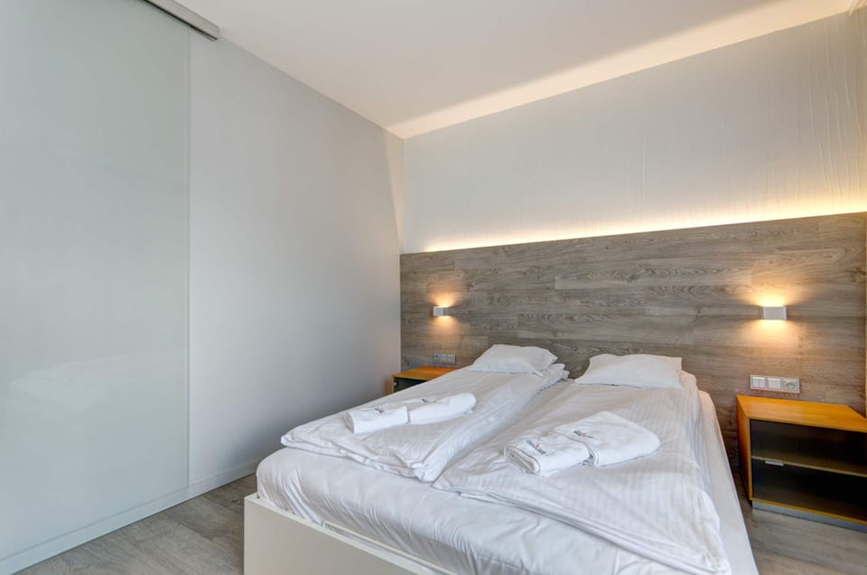In the bedroom, the bedside tables will provide space for the most necessary things, and the sliding glass door adds a modern touch to the interior. 