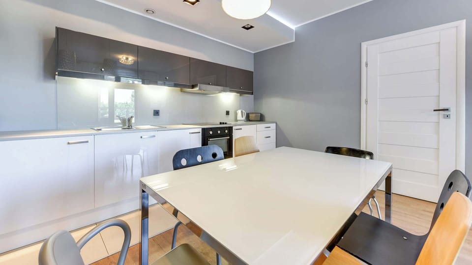 Fully equipped kitchenette with electric cooktop, electric kettle, refrigerator, freezer, oven, toaster, dishwasher and table with chairs.