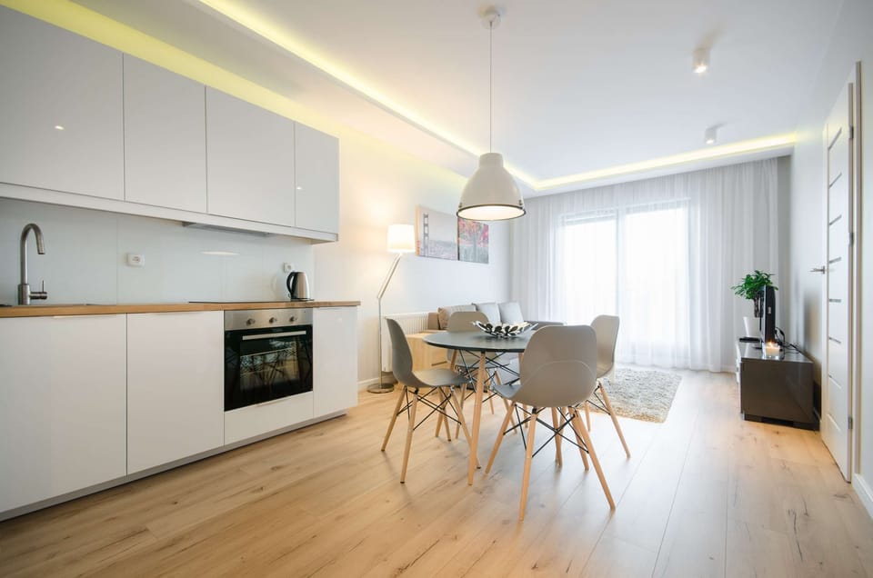 Bright lving room with a sofa, TV and kitchenette with dining area.