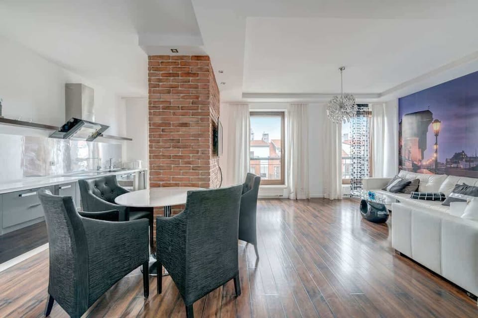 The industrial touch of the brick wall introduces an interesting contrast, creating a pleasant atmosphere for unwinding. The panoramic window offers a patio view, and the flat-screen TV completes the space.