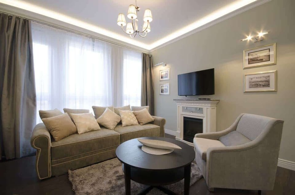 The sofa is surrounded by tasteful furniture – a round, black coffee table and a comfortable, upholstered armchair, creating a cozy relaxation corner. 