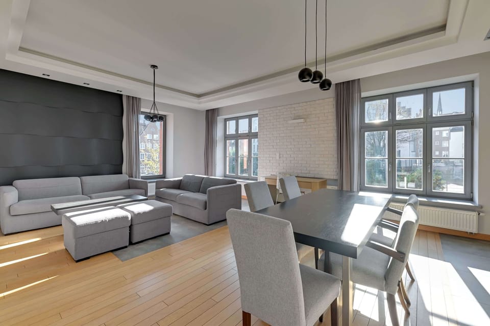 A cozy living area featuring stylish gray furniture, a bright window, and an open-plan layout with a dining area.