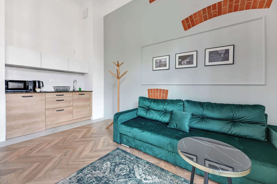 A cozy space featuring a teal sofa, framed artwork, and large windows letting in natural light.